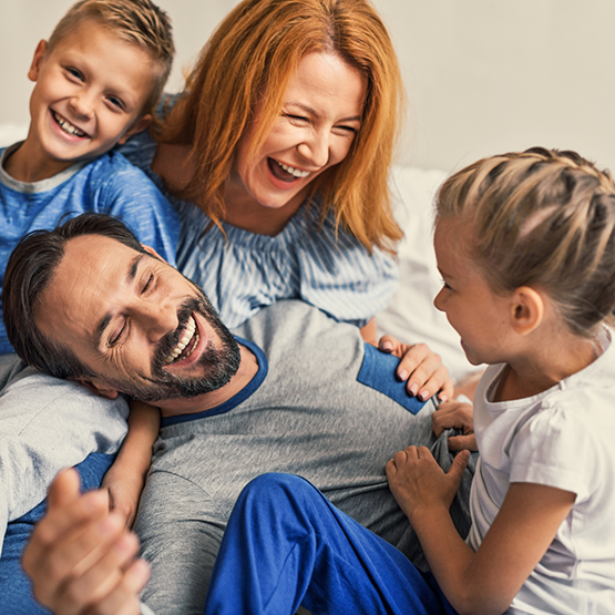 Family of four sitting on a bed and laughing