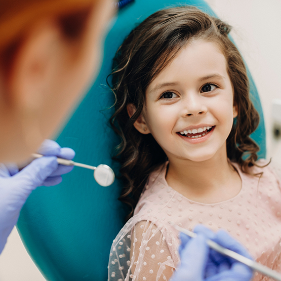 Young girl grinning at her dentist during dental checkup