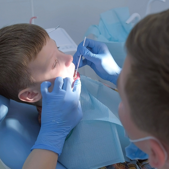 Young boy having fluoride applied to his teeth by dentist