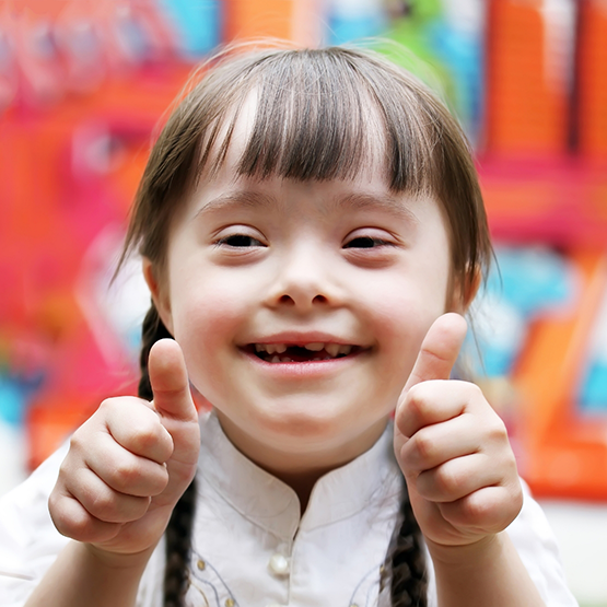 Young girl with special needs smiling and giving thumbs up