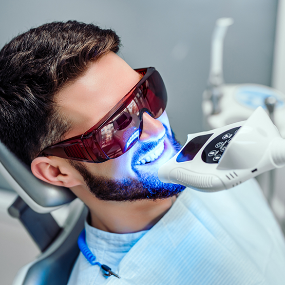 Man in dental chair receiving professional teeth whitening