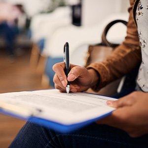 Woman filling out dental insurance form in lobby