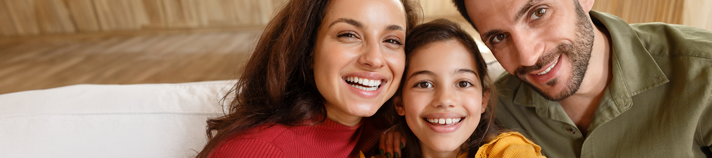 Family of three grinning in their home