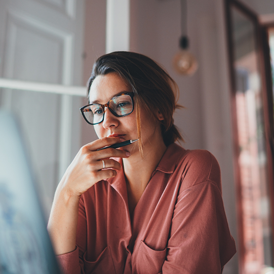 Woman looking contemplative while starting at computer screen