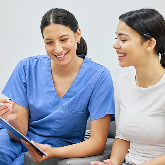 Patient and dental team member looking at clipboard