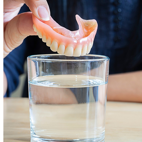 Person placing a denture in a glass of water