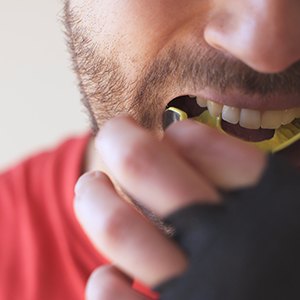 Man in red shirt inserting yellow mouthguard