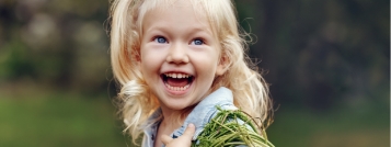 Blonde child grinning outdoors