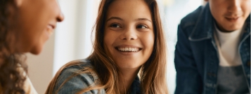 Teenage girl smiling at person sitting next to her