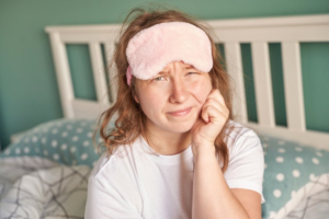 Woman with bedtime eye mask rubbing her toothache